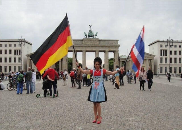 Thai Masseurin vor Brandenburger Tor mit zwei Flaggen